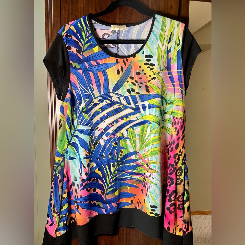 Short sleeved tropical print tunic with black band on the asymmetrical bottom.